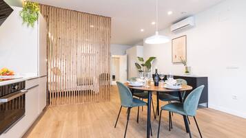 Un comedor moderno con una mesa redonda, cuatro sillas y una lámpara colgante.