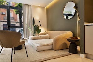 A modern living room with a sofa, a chair, a round mirror, and a side table.