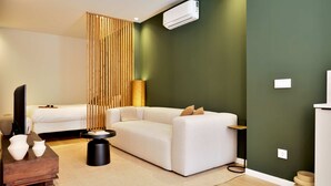 A modern living room with a white sofa, a wooden side table, and a small black side table. - SariStays Valencia Modern & Luxury 3 (València)