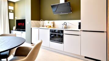 Una cocina moderna con horno empotrado, microondas y un televisor mostrando 'NETFLIX'.