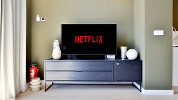 Una sala moderna con un televisor de pantalla plana sobre un mueble de madera oscura, un florero y un extintor.