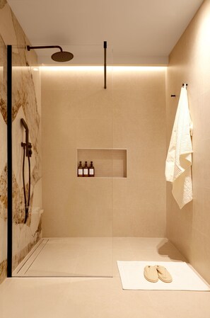 A modern bathroom with a glass-enclosed shower, a towel rack, and a shelf with bottles.