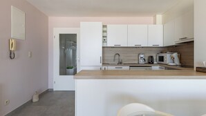 A modern kitchen with white cabinets, a wooden countertop, and a coffee maker.