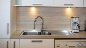A modern kitchen with a stainless steel sink, a coffee maker, and wooden cabinetry.
