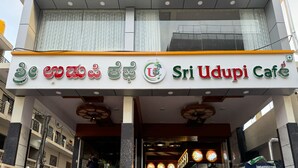 De gevel van Sri Udupi Cafe, met een bord waarop de naam en het logo van de café staan.