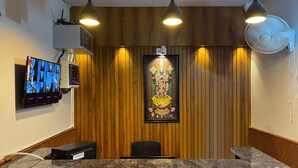 Een receptiezone met een houten paneelwand, een lijst met religieuze icoon, een digitale fotopresentatie en een receptiebalie.