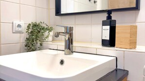 Une salle de bain avec un lavabo blanc, un miroir et un distributeur de savon liquide.