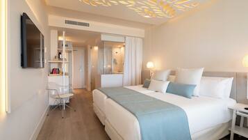 Habitación de hotel con una cama grande, un escritorio, una silla, un espejo y una lámpara en el techo.