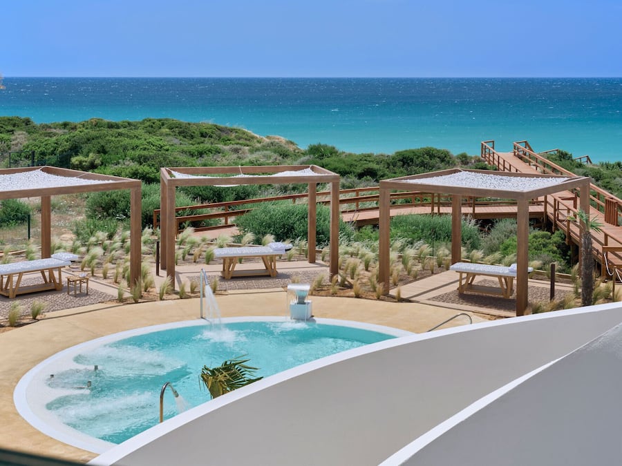Un espace piscine agrémenté de pergolas en bois, de bancs et offrant une vue sur l’océan.