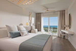 A modern hotel room with a large bed, a desk, a chair, and a balcony with a view.