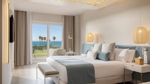 A modern hotel room with a large bed, a desk, and a view of the ocean. - Amàre Beach Hotel Sancti Petri - Adults Recommended (Chiclana de la Frontera)