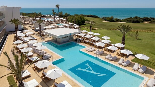 A resort with a swimming pool, sun loungers, umbrellas, and a view of the sea. - Amàre Beach Hotel Sancti Petri - Adults Recommended (Chiclana de la Frontera)