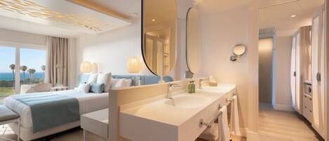 Ein modernes Hotelzimmer mit einem großen Bett, einem Doppelwaschbecken und einem großen Spiegel.