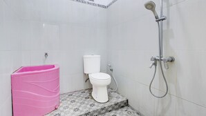 Um banheiro com vaso sanitário, chuveiro e uma lixeira rosa.