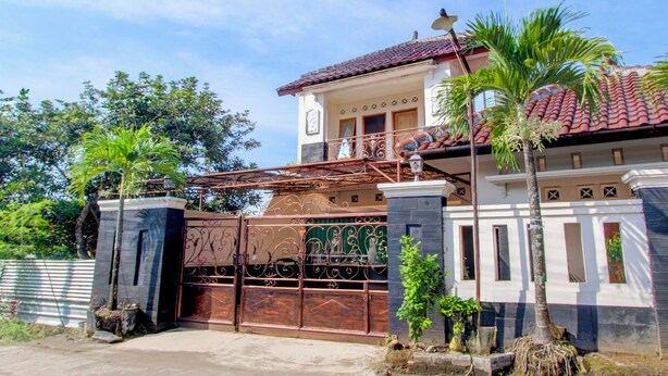 Uma casa de dois andares com portão, varanda e telhado em cerâmica.