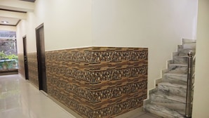 A hallway with a tiled wall, a marble staircase, and a metal handrail. - Laugh Tale Hostel (Rishikesh)