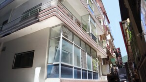 A multi-story building with large windows, balconies, and a sign indicating a guest house. - Laugh Tale Hostel (Rishikesh)