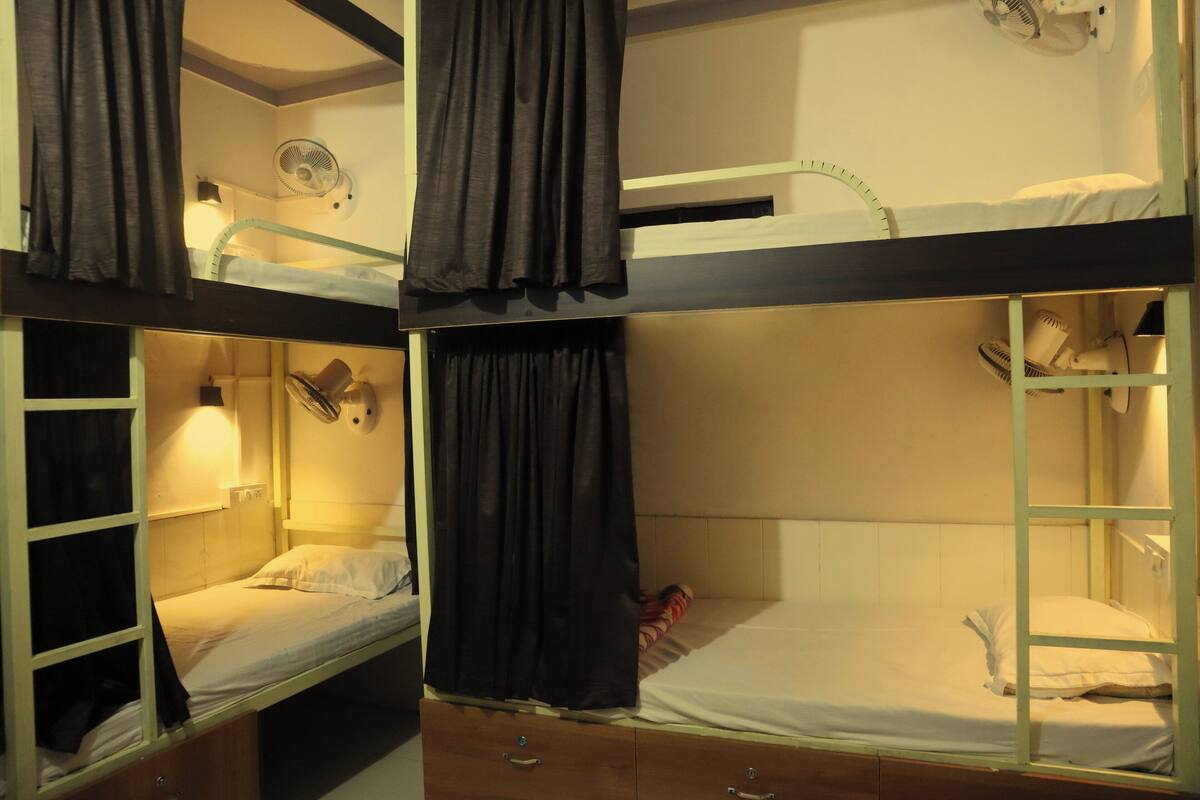 Habitación tipo dormitorio con literas, cada una con mesita de noche y lámpara.