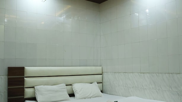 A modern bedroom with a bed, a ceiling fan, and a small table. - Laugh Tale Hostel (Rishikesh)