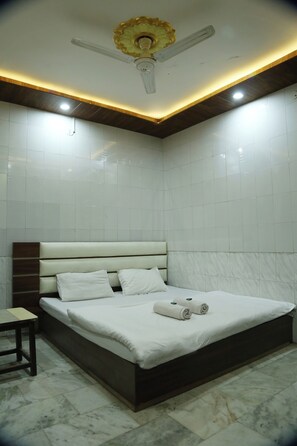 Une chambre à coucher moderne avec un lit, un ventilateur de plafond et une petite table.