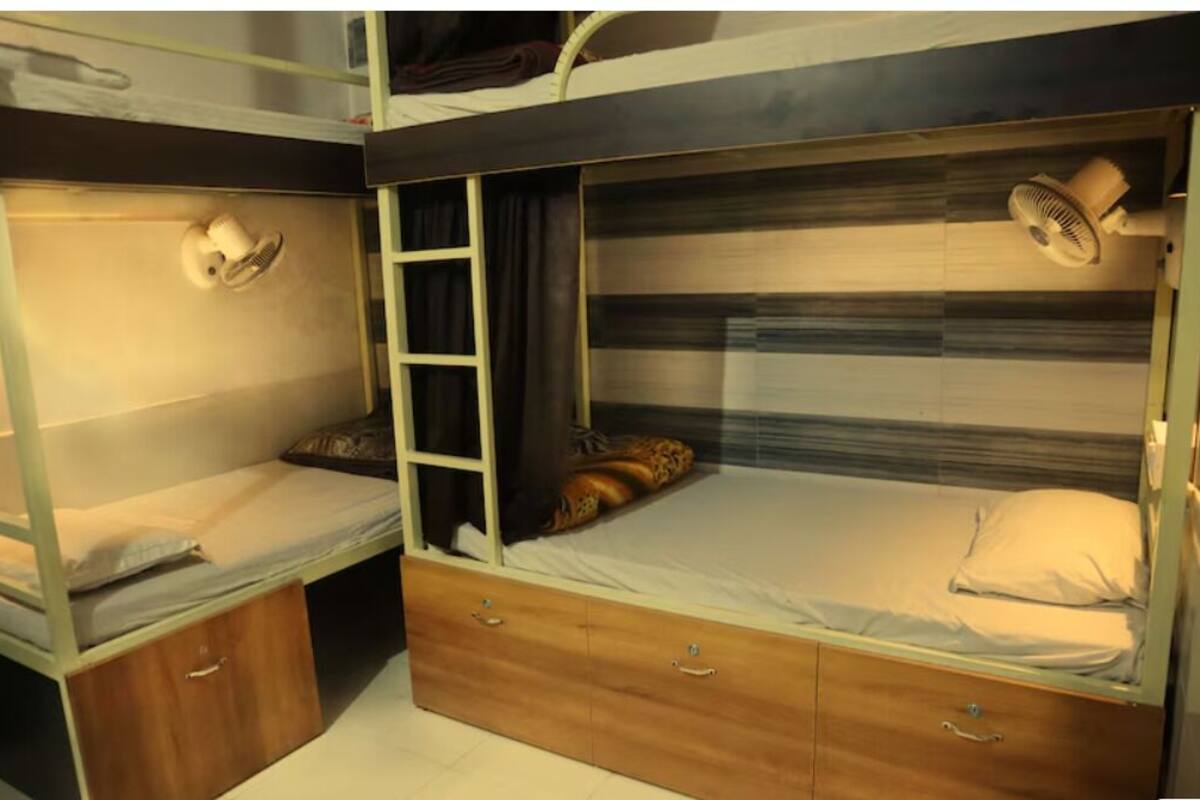Habitación con literas, una escalera, cajones y un ventilador.