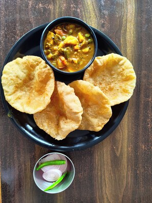 A plate with several pieces of flatbread and a bowl of vegetable curry.