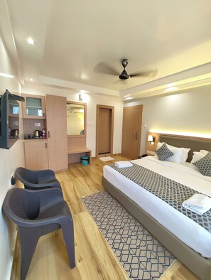 A modern hotel room with a large bed, a desk with a chair, a wardrobe, and a ceiling fan.
