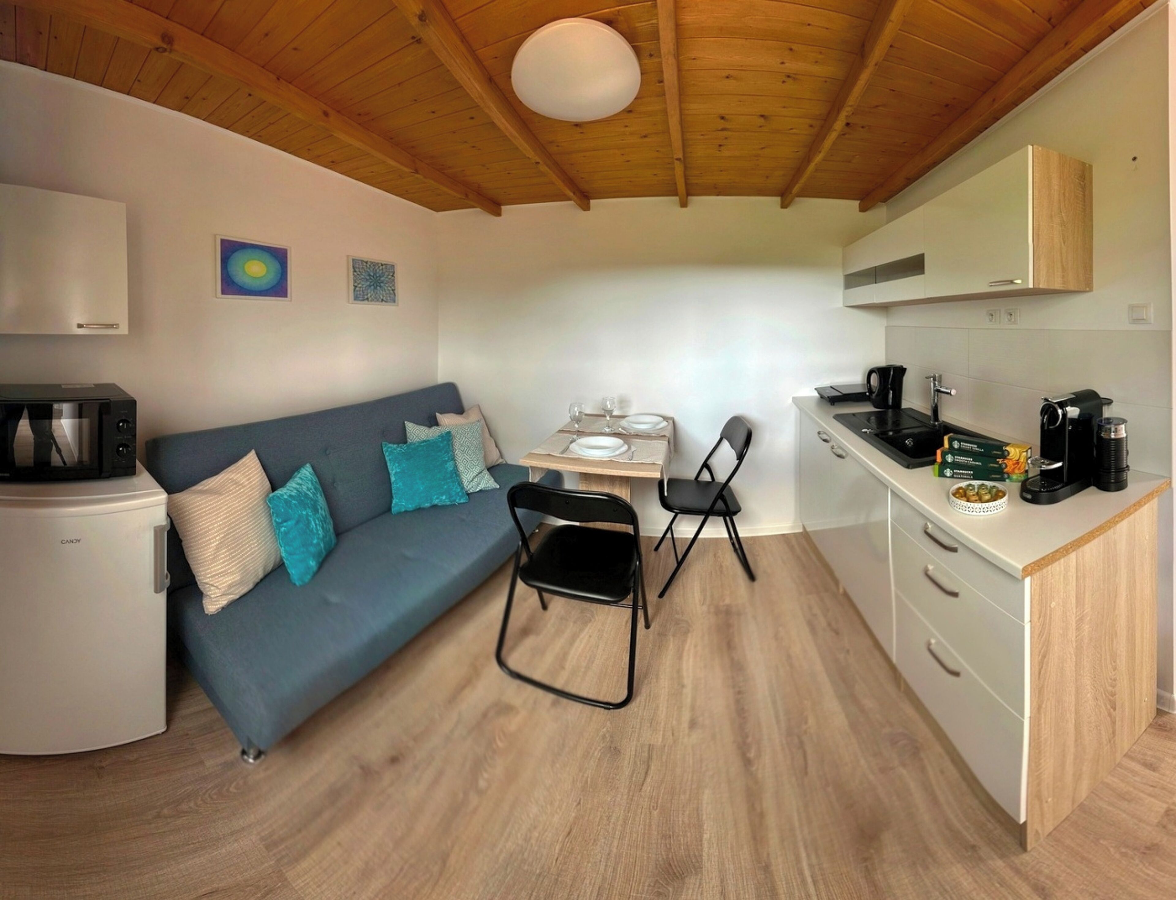 A compact living space with a kitchenette, a dining area, and a sofa.