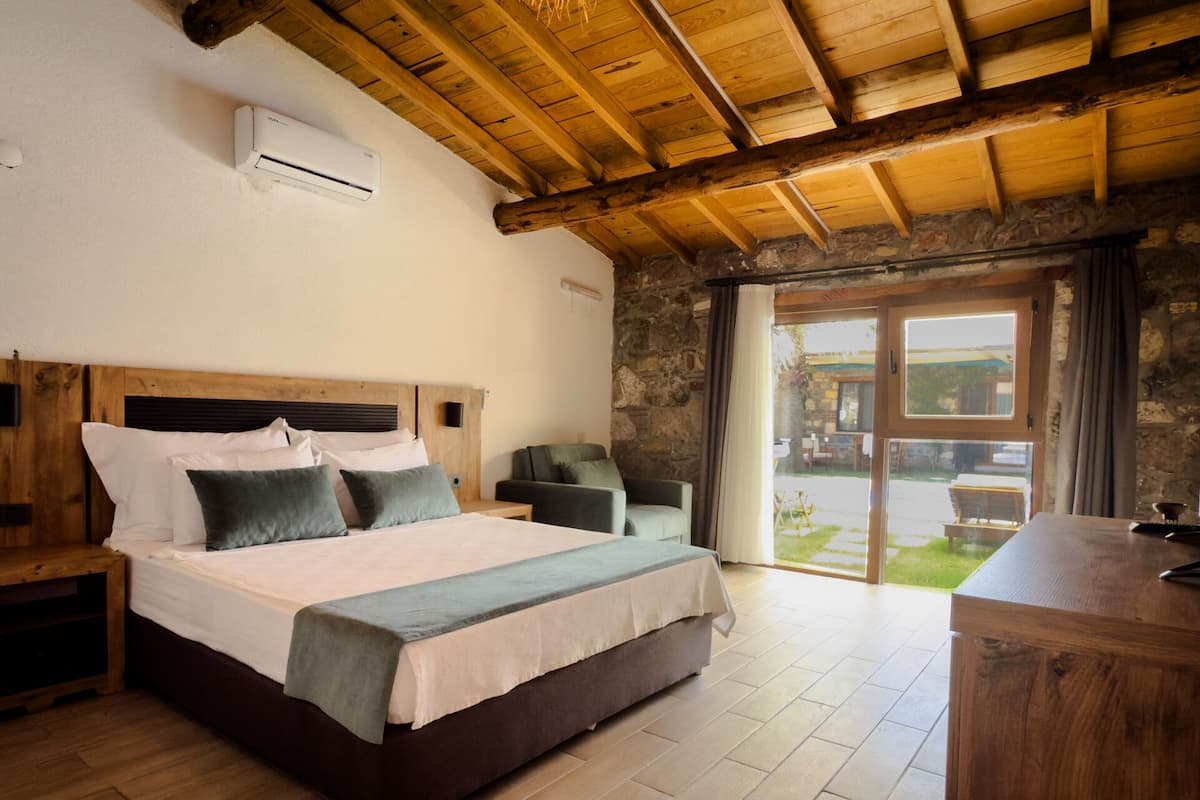 Une chambre avec un lit en bois, une table de chevet, une chaise et une vue sur l’extérieur grâce à une porte vitrée.