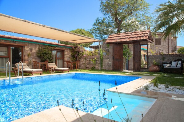 Piscina com espreguiçadeiras e área de estar coberta.