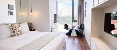 A modern hotel room with a large bed, a desk, a chair, and a TV.