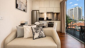 Un apartamento moderno con sofá, cocina y ventanas amplias que dan a vistas de la ciudad.