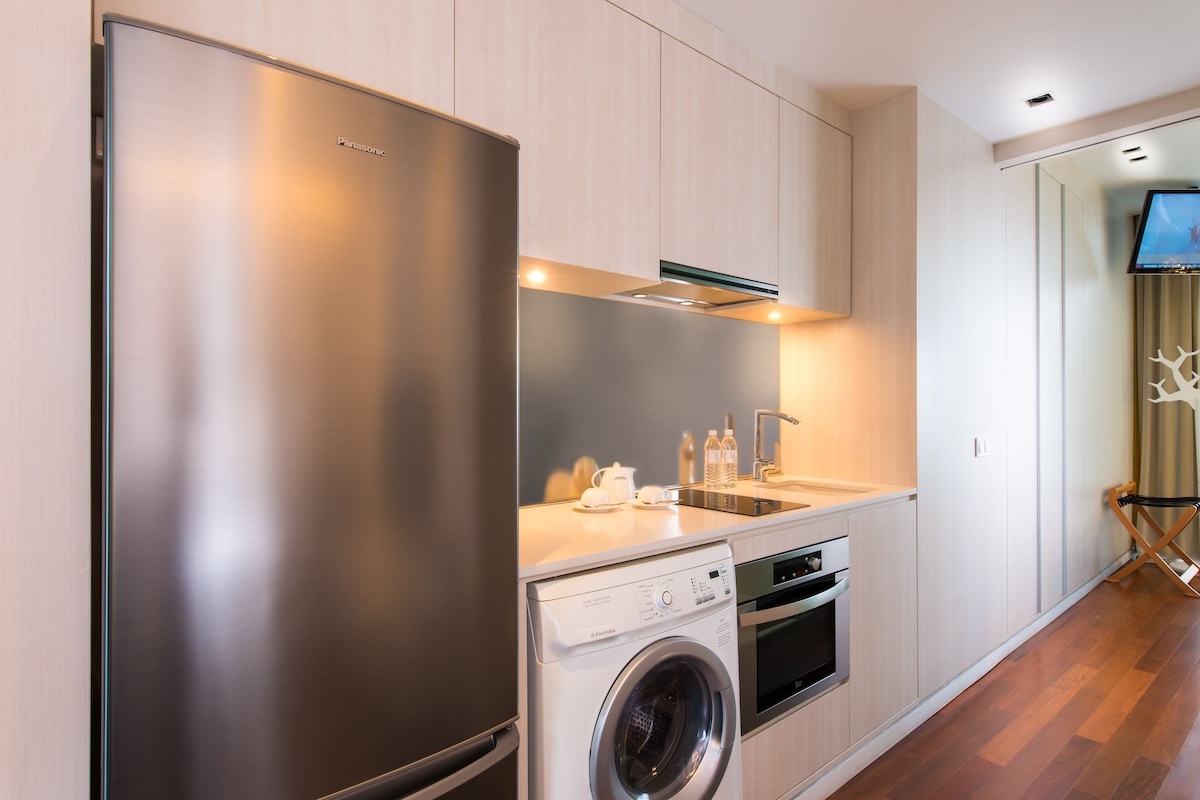 Uma cozinha moderna com frigorífico de aço inoxidável, máquina de lavar embutida e micro-ondas.