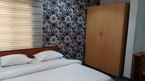 A bedroom with a bed, a wardrobe, and a patterned wallpaper. - Calawazobia hotel (Uyo)