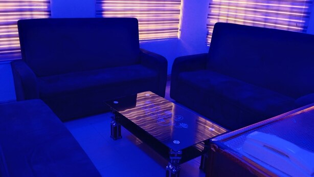 A living room with two sofas, a glass coffee table, and a wooden side table. - Calawazobia hotel (Uyo)