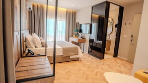 A modern hotel room with a bed, a desk, a mirror, and a view of the outdoors. - Vila Lasko (Golem)