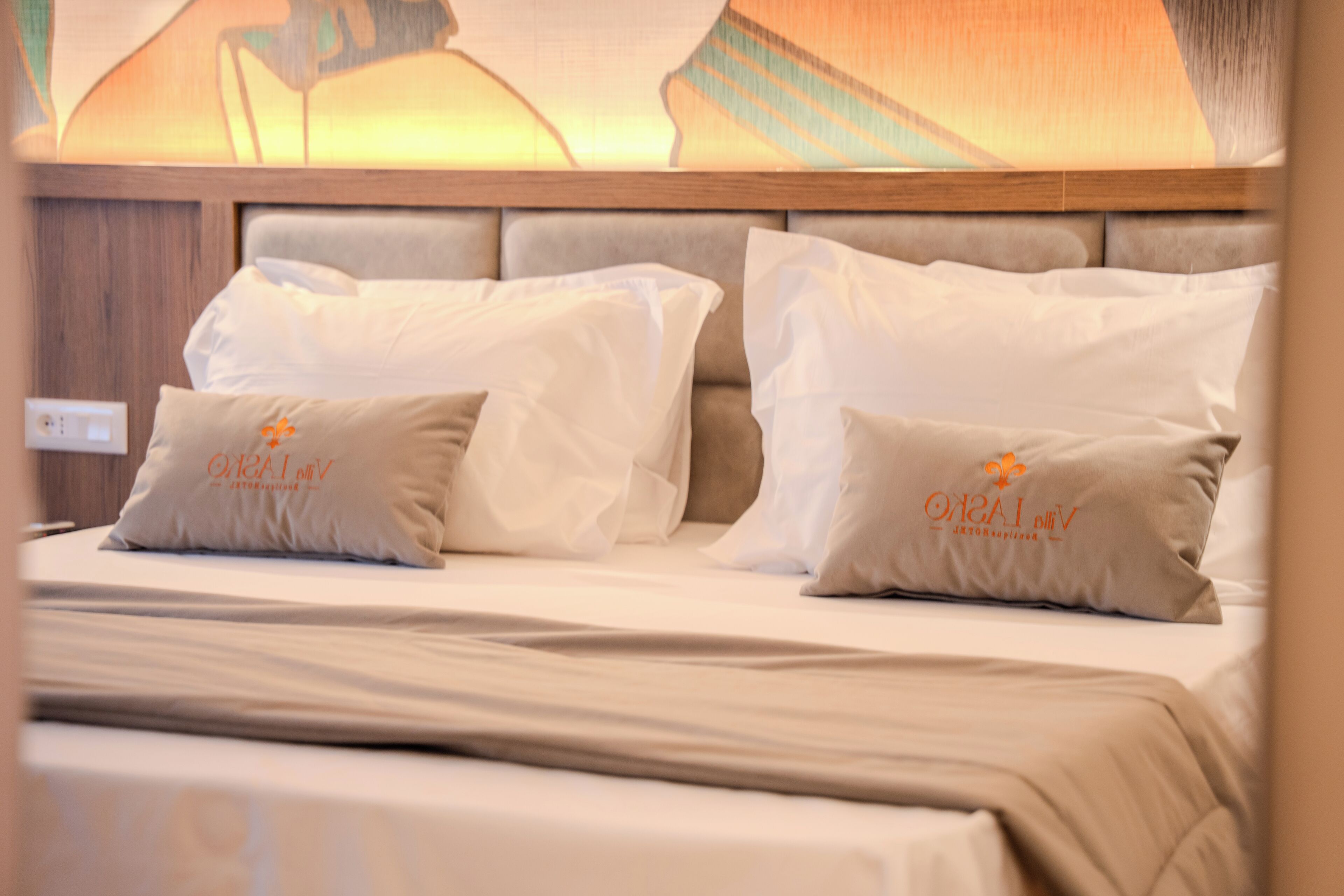 A hotel room with a bed, headboard, and pillows.