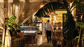 A restaurant with wicker chairs, a bar area, and a display case with bottles. - Vila Lasko (Golem)