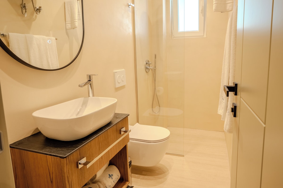 A bathroom with a large white sink, a toilet, a shower, and a mirror.