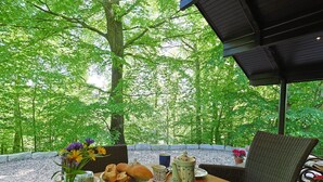 Een eethoek buiten met een tafel gedekt voor het ontbijt, omringd door weelderige begroeiing.