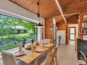 Un interno in legno con un tavolo da pranzo per due persone, un angolo cottura e vista su un paesaggio verde.