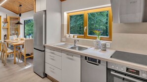 Een moderne keuken met houten balken in het plafond, een roestvrijstalen koelkast, een vaatwasser en een oven.
