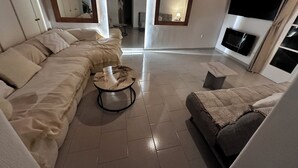 Una sala de estar moderna con un sofá, una mesita redonda y un televisor montado en la pared.