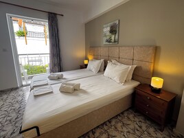 Habitación de hotel con una cama grande, dos mesitas de noche con lámparas, un balcón con vistas y un cuadro en la pared.