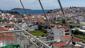A coastal cityscape with red-tiled rooftops, a view of the sea, and a bridge in the foreground. - Skiathos Platis House (Skiathos)