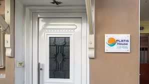 A white door with a glass panel and a decorative top. A sign with the text "PLATIS House" is mounted on the wall to the right of the door. - Skiathos Platis House (Skiathos)