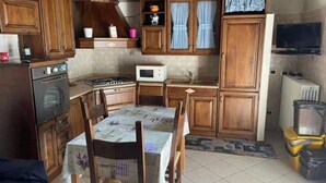 Une cuisine compacte dotée de meubles en bois, d’un four à micro-ondes, d’une cuisinière et d’une table à manger avec des chaises.