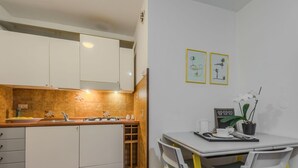 A compact kitchen with white cabinets, a wooden countertop, and a small dining area with a table and chairs.