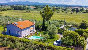 Una casa con piscina, immersa nel verde e con vista sulle montagne lontane.