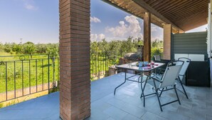 Un portico coperto con un pilastro in mattoni, posti a sedere all'aperto e vista su un vigneto.